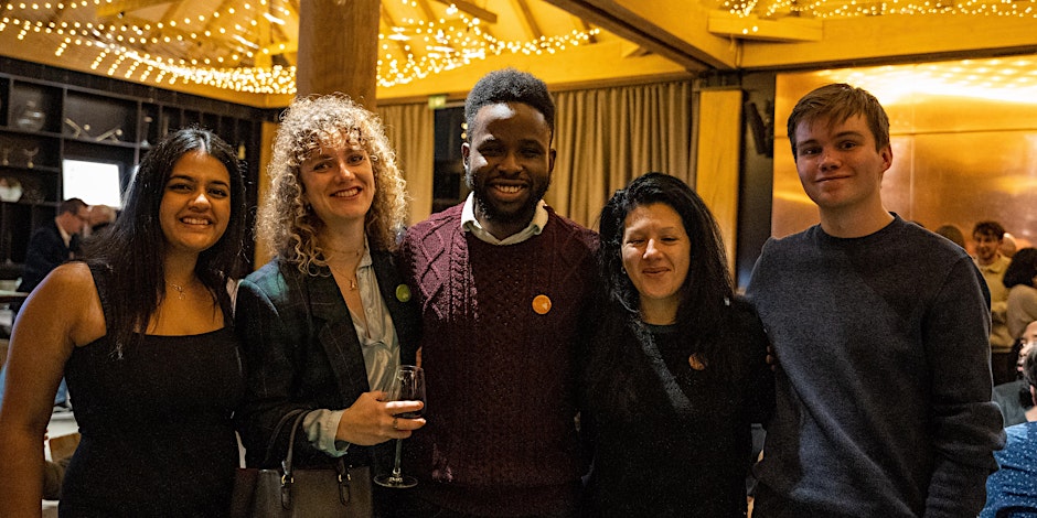 People in a festive environment. Holding drinks, looking at the camera and smiling.