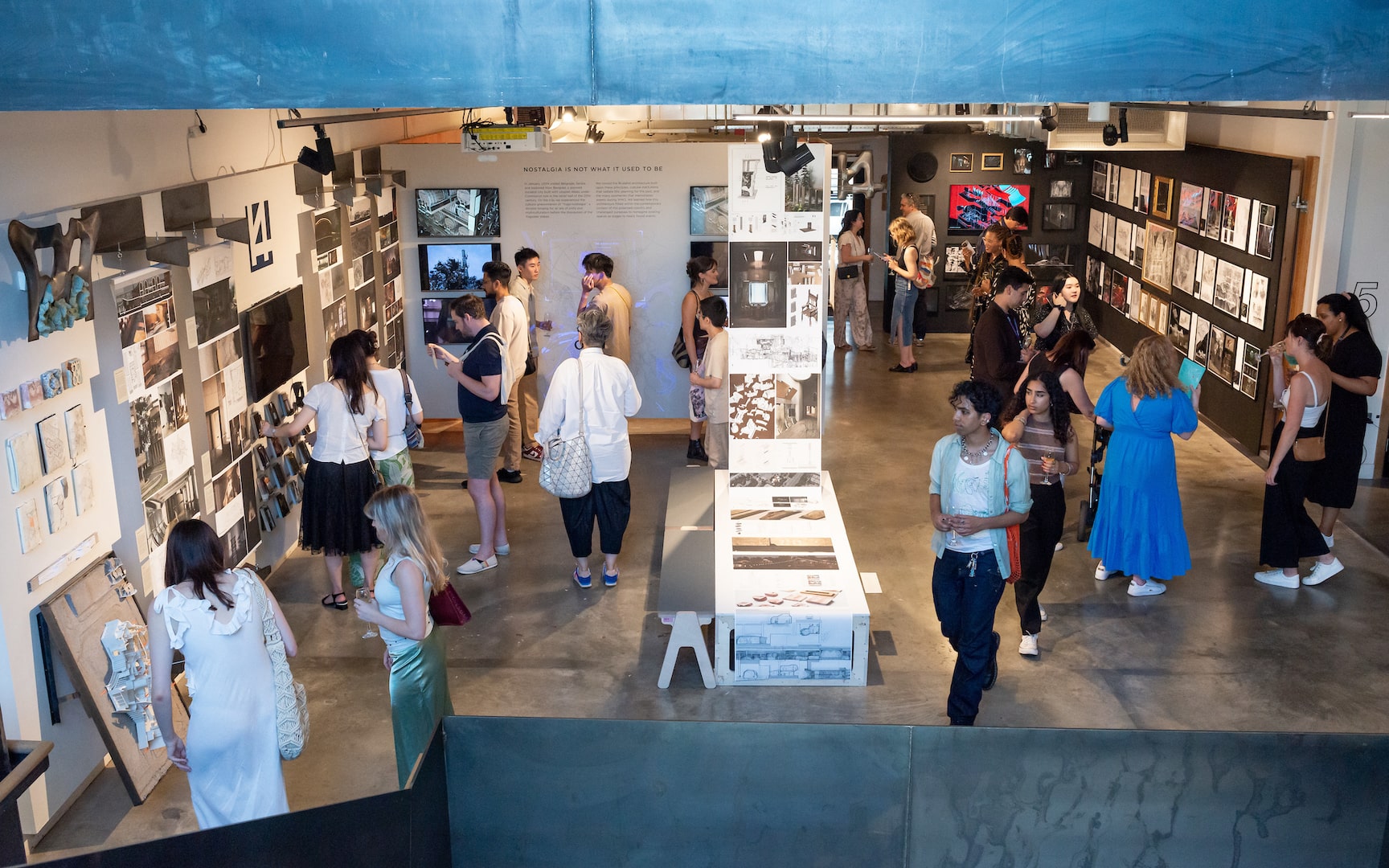 Visitors exploring exhibits at the Bartlett Summer Show 2023, featuring architectural models, sketches, and multimedia displays in a vibrant gallery setting