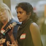 Niya speaking into a microphone at the Women in Architecture (WiA) mentoring closure event in London