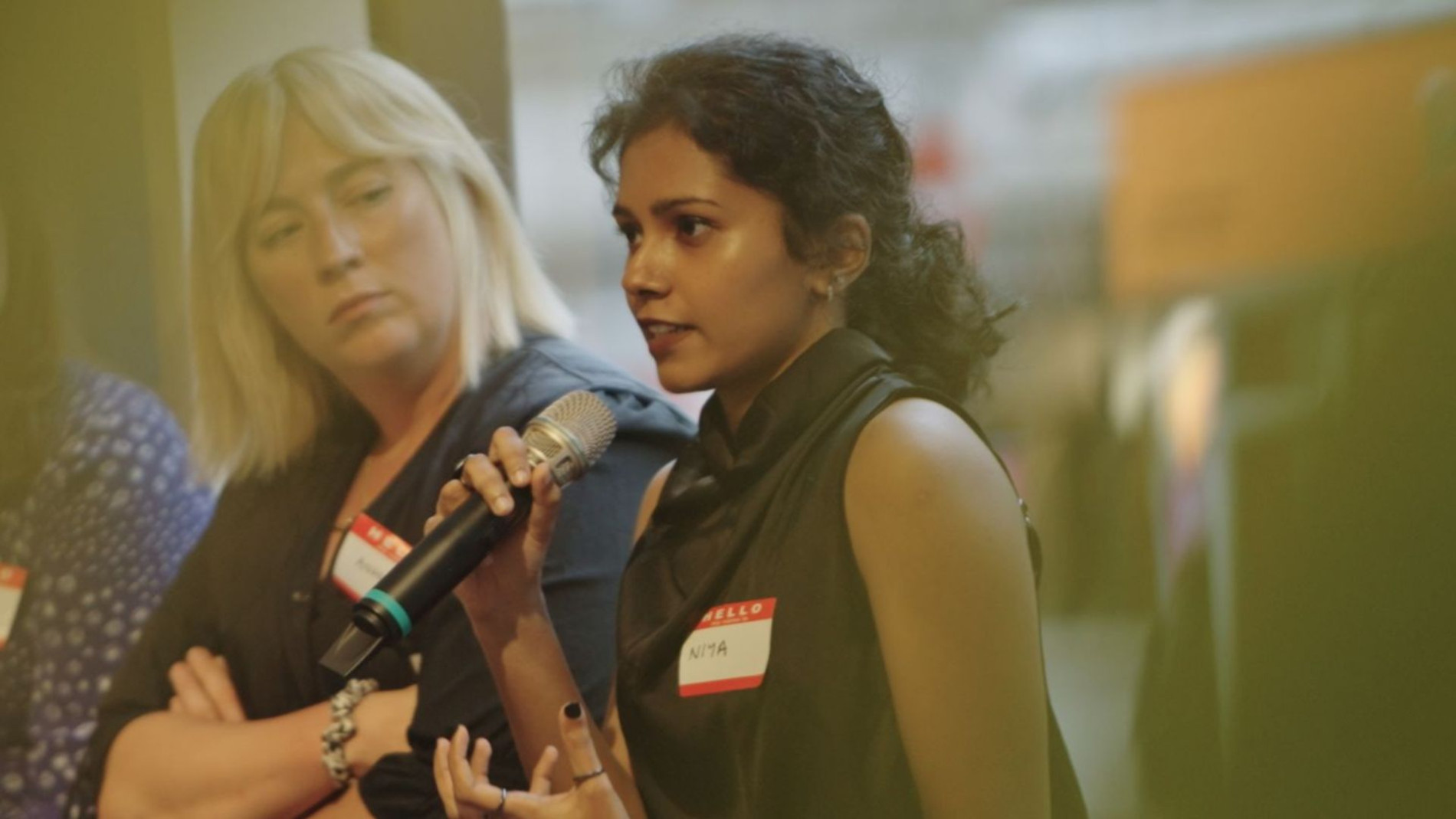 Niya speaking into a microphone at the Women in Architecture (WiA) mentoring closure event in London