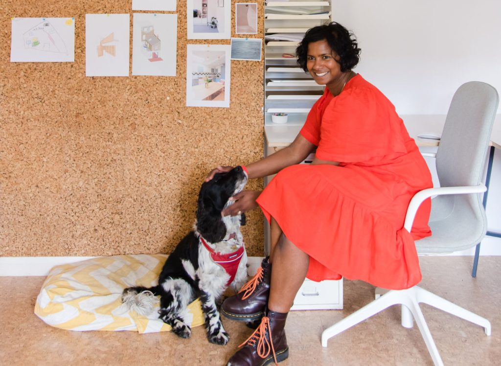Nimi in orange dress in office. Patting dog