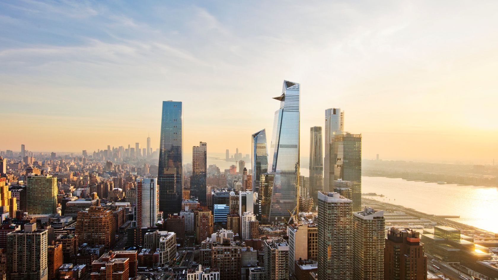 View of Hudson Yards in New York City at sunset, showing a cluster of KPF-designed skyscrapers rising above Manhattan’s West Side, with the Hudson River visible in the background.