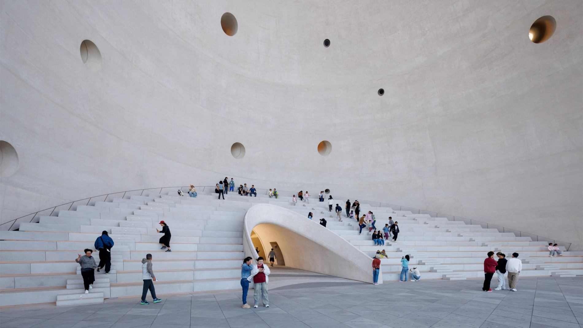 Photo of a museum hall with people sat and stood.