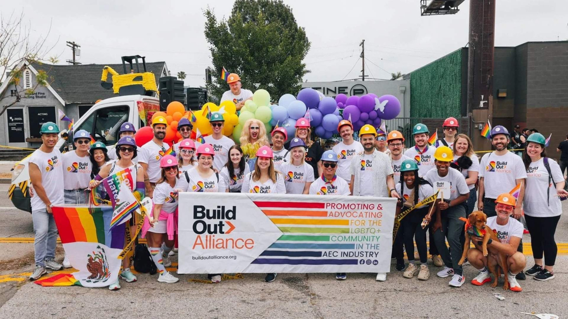 Group of Build Out Alliance members wearing rainbow hard hats and t-shirts, holding a banner that reads “Promoting & Advocating for the LGBTQ+ Community in the AEC Industry” during a Pride event in Greater Los Angeles.