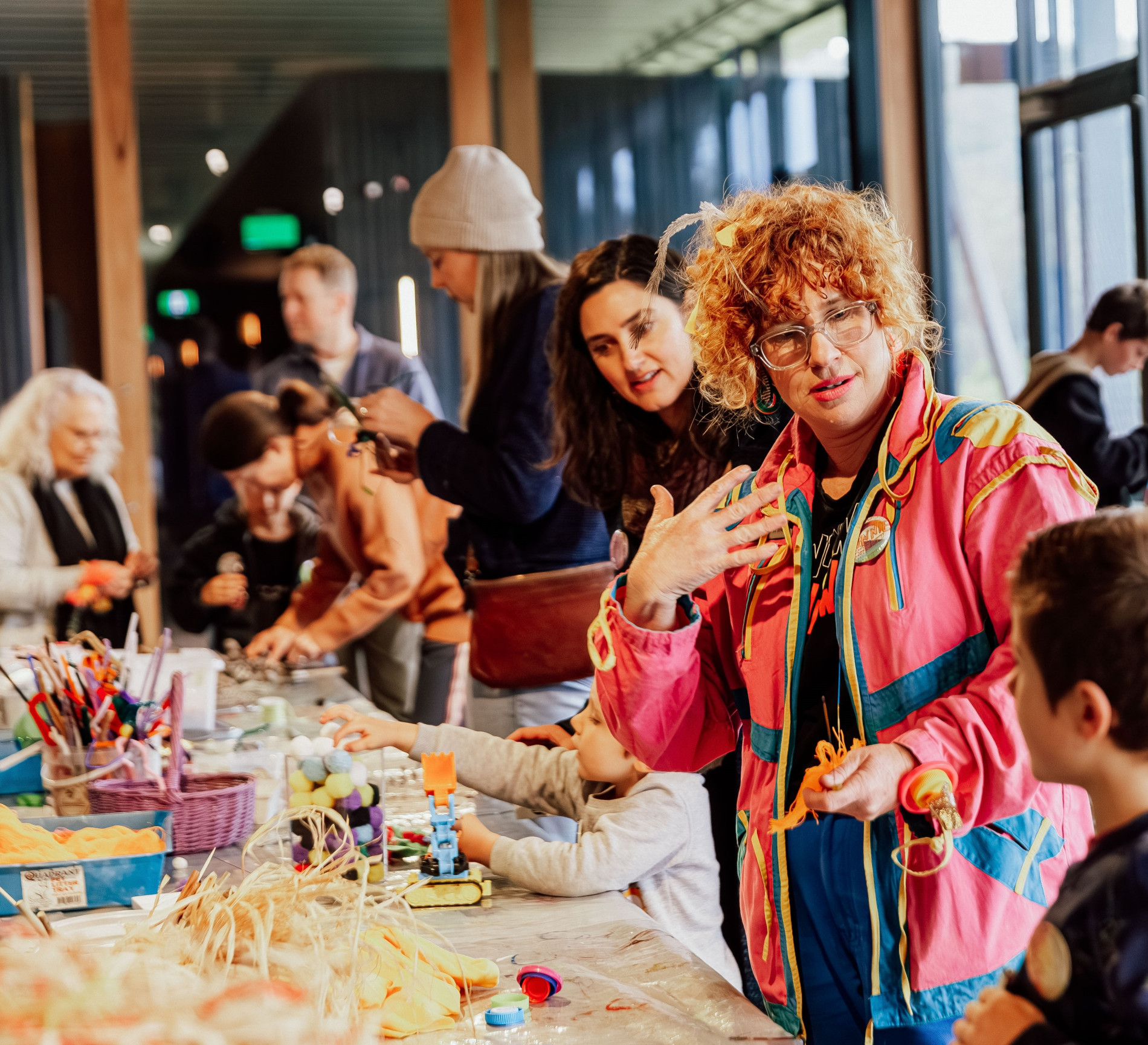 Photo of two people speaking in a room where a craft workshop is taking place