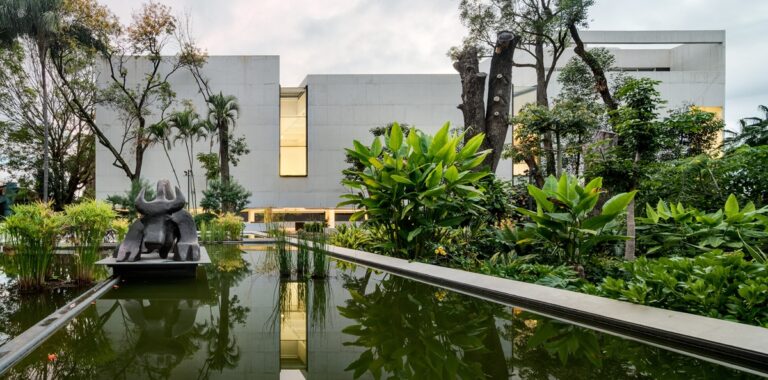 Photo of white / concrete building surrounded by lush greenery