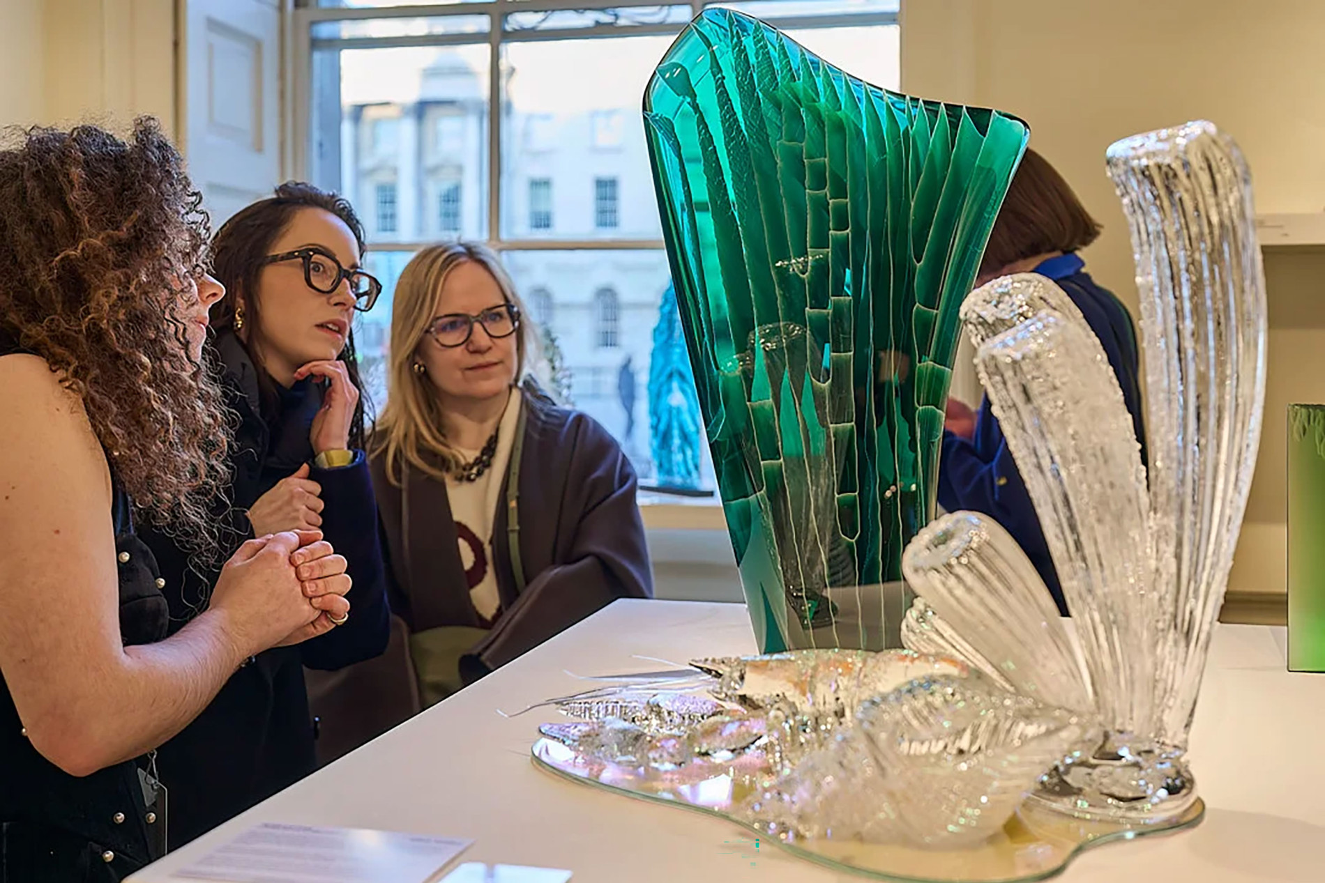 Photo of three people viewing glass sculpture