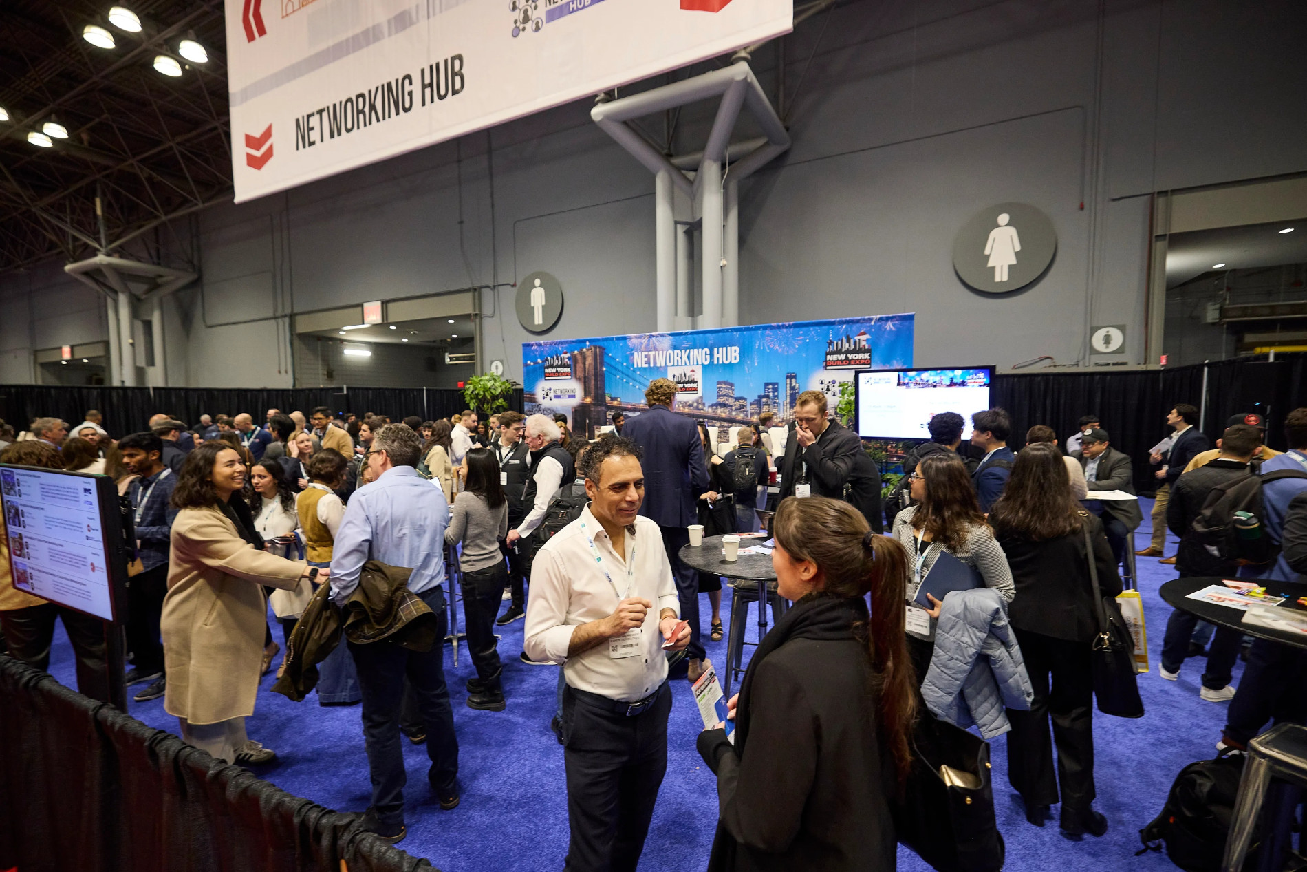 People networking in a conference hall with stands