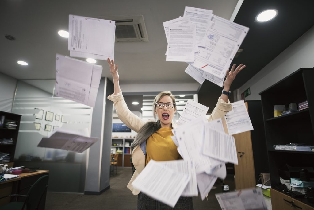 Stressed woman throws papers in the office in an image of relief
