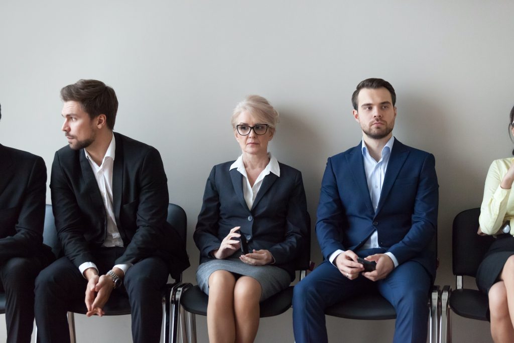 Group of serious young and middle aged candidates professionals business people sitting in chairs in queue waiting job interview, for one position at company. Human resources, hr, recruitment concept (Group of serious young and middle aged candidates
