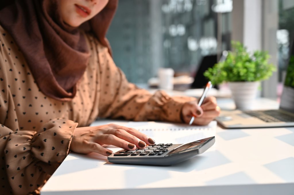 Islam woman working with finance calculate on calculator.