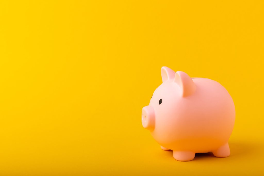 A photo of a pink piggy bank on a yellow background.
