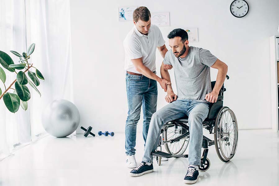 Physiotherapist helping man in Wheelchair during recovery in hospital